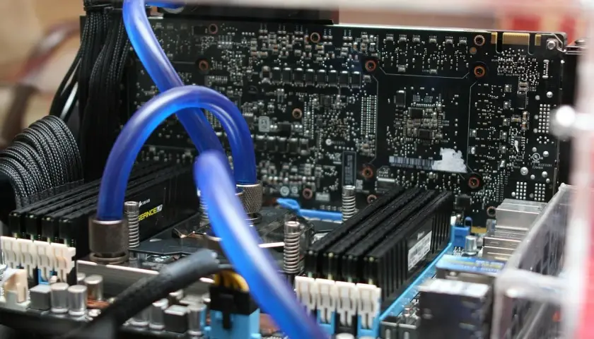 Composants d'un PC, dont des tubes bleus de watercooling et des barrettes de RAM. Utile pour connaître sa carte mère Windows 10.