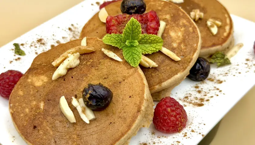 Pancake farina di castagne con lamponi, mirtilli, mandorle e menta. Un dolce autunnale invitante.