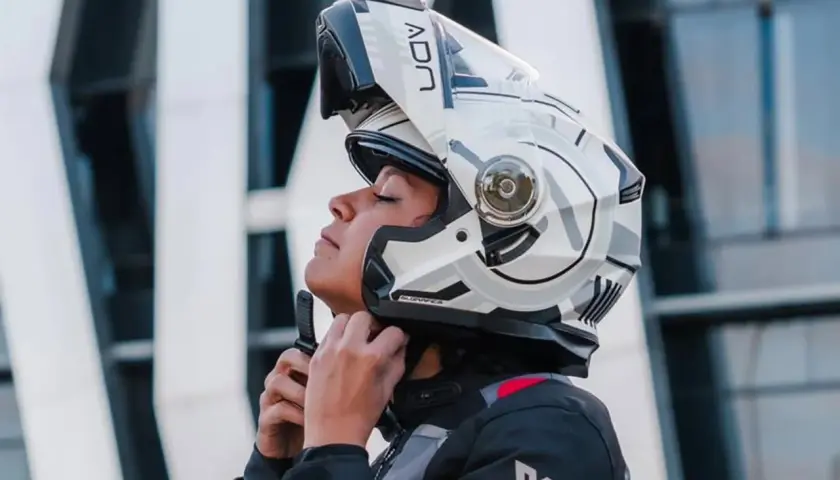 Mujer ajustando su casco integral o modular, listo para la aventura.