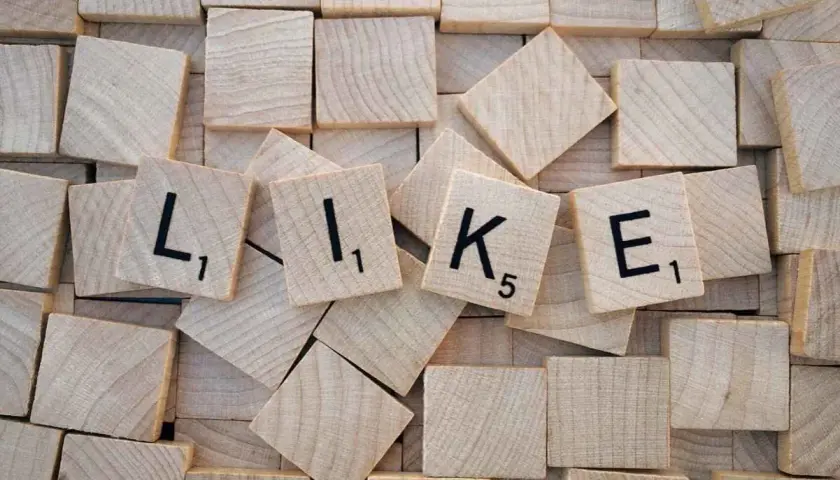 Wooden tiles spelling out "LIKE" with black letters and numbers.