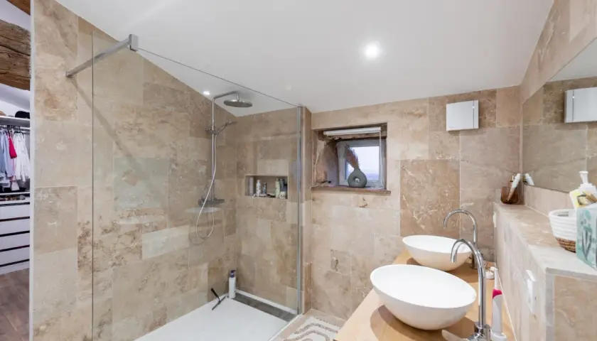 Salle de bain moderne aux tons sable, avec douche à l'italienne, double vasque et dressing attenant. Un exemple de travaux rénovation salle de bain réussis.