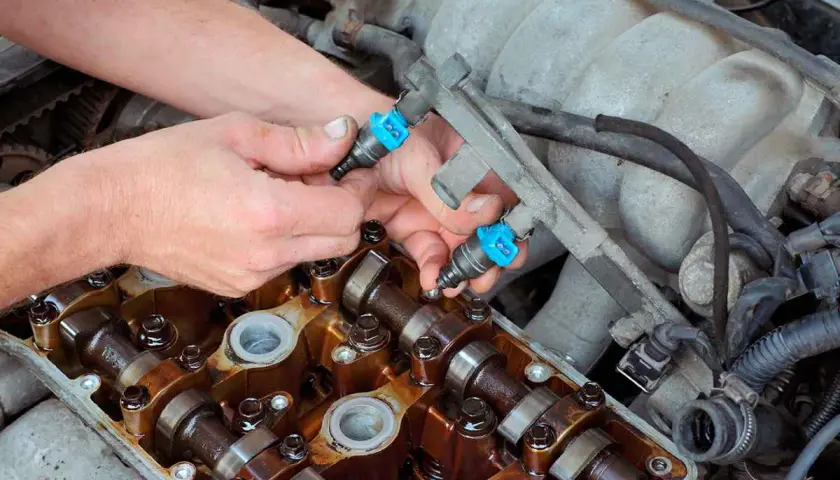 Mecánico instala inyectores de combustible en un motor. Aunque se puede circular con un inyector averiado, es mejor repararlo.