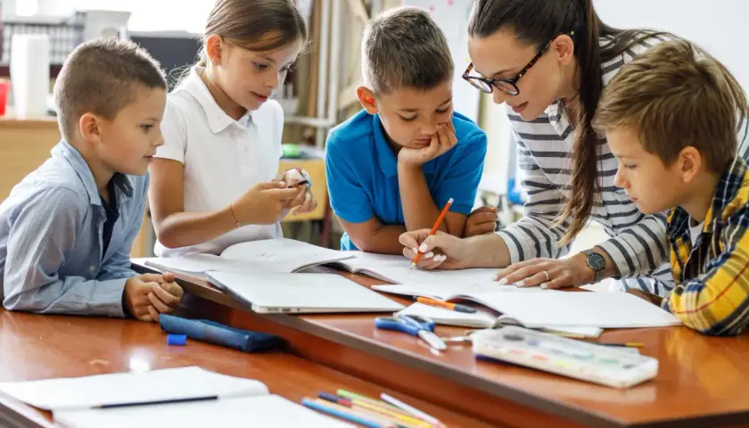 Lehrerin hilft Kindern bei der **weiterbildung berufsbegleitend**. Sie lernen gemeinsam im Unterricht.