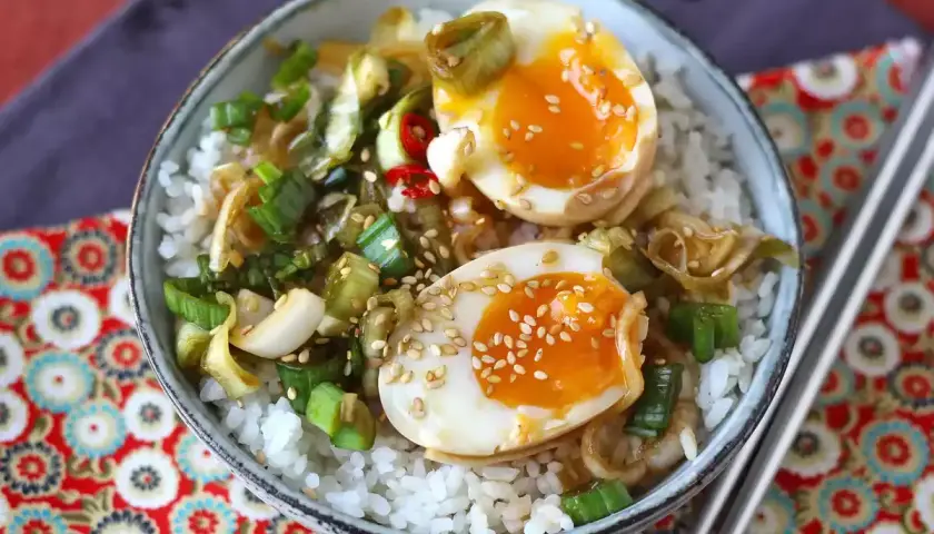 Skål med ris, halverade mayak gyeran-ägg med krämig gula, salladslök och sesamfrön.