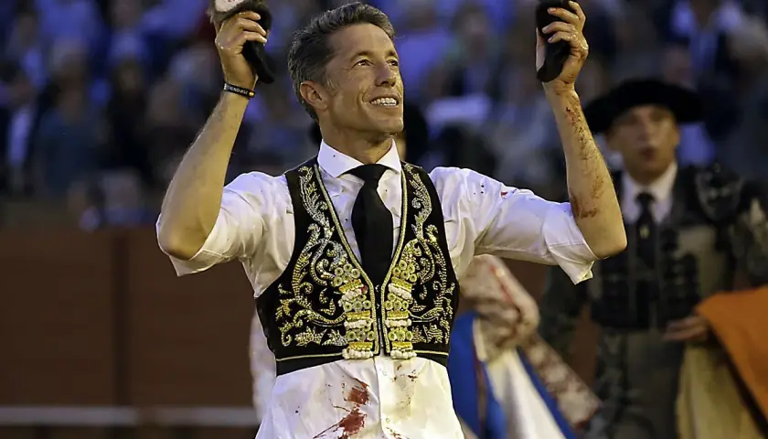 Manuel Escribano, triunfador, levanta las orejas del toro en la plaza.