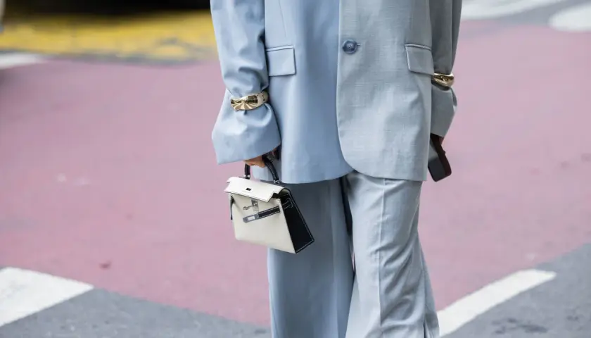 Traje gris con pantalones de pierna ancha (wide leg significado) y bolso blanco y negro.