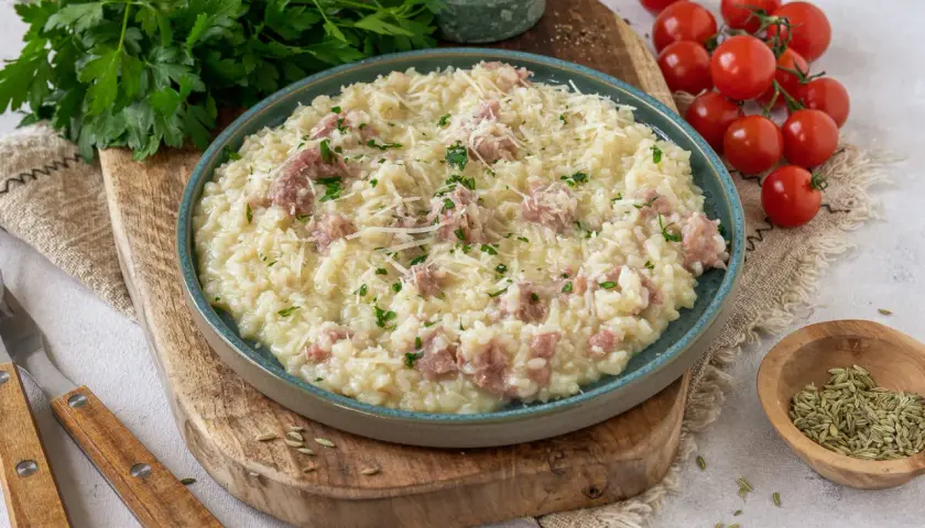 Cremiges Risotto mit Salsiccia, garniert mit Parmesan und Petersilie, serviert auf einem rustikalen Holzbrett.