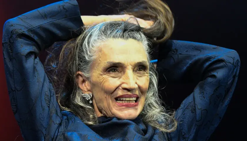 Mujer con peinados pelo largo liso, plateado y castaño, sonriendo y tocándose el cabello con las manos.