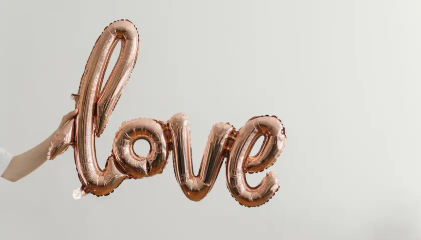 Różowe balony w kształcie napisu "love" unoszą się w powietrzu, tworząc piękną definicję miłości.