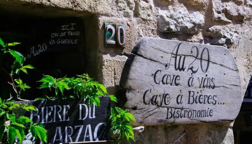 Bonjour! Drewniany szyld "Au 20" zaprasza do piwnicy z winami i piwami. Obok tablica z napisem "Biere du Arzac".