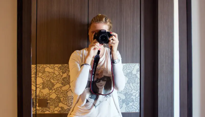 Dziewczyna z aparatem w rękach, ćwiczy na zajęciach szkoły fotografii.