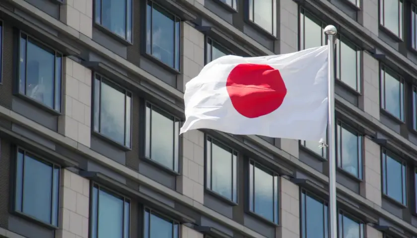 Flaga Japonii powiewa przed nowoczesnym budynkiem. Japonia liczba ludności to ponad 125 milionów osób.