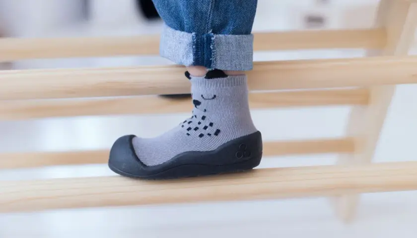 Szare skarpeto-buty z misiem, idealne dla dziecka z wysokim podbiciem, zapewniające komfort i bezpieczeństwo podczas zabawy.