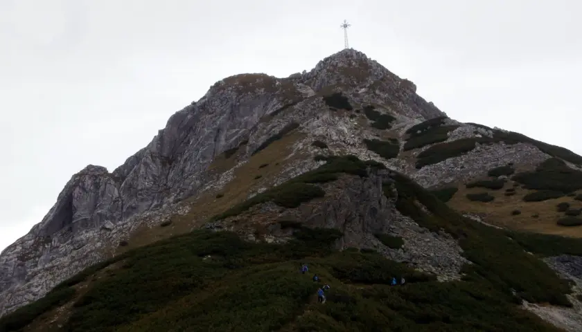 Wspinaczka na Giewont, gdzie w trudnym terenie pomagają łańcuchy. Widok na szczyt z krzyżem.