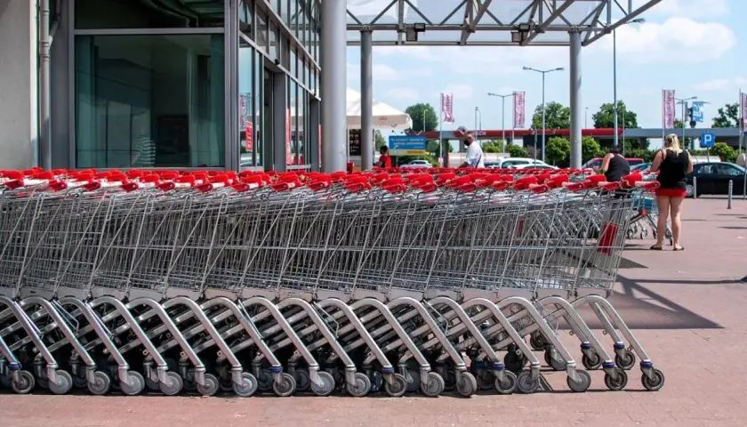 Rzędy wózków sklepowych z czerwonymi uchwytami przed francuskim hipermarketem.