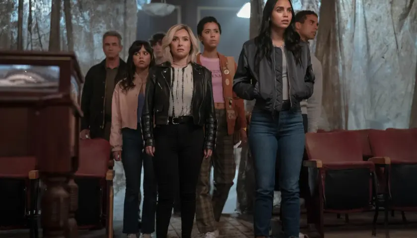 Grupa młodych ludzi, w tym Melissa Barrera i Jenna Ortega, stoi w przerażeniu. To krzyk 7 obsada, która właśnie odkryła coś strasznego.