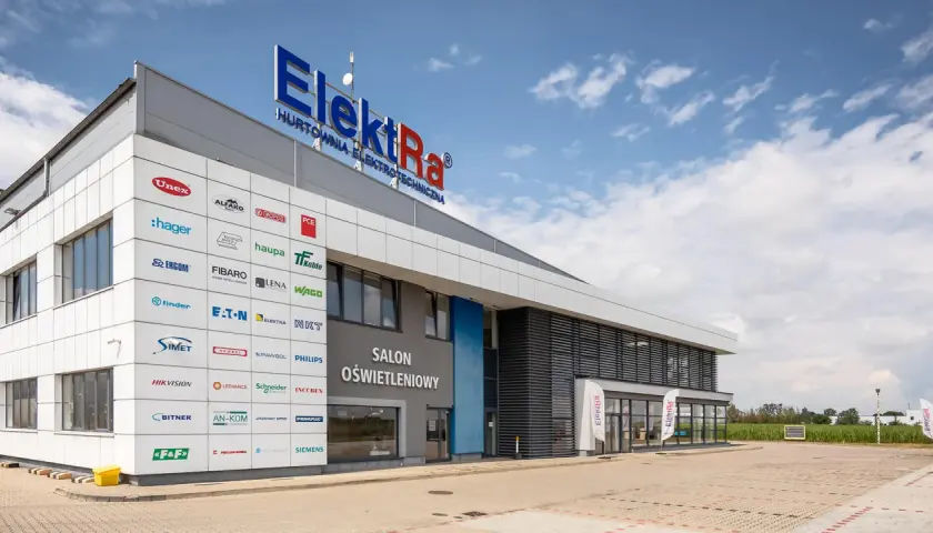 Nowoczesny budynek hurtowni z art elektrotechnicznymi Elektra Śrem. Na fasadzie widoczne liczne logotypy znanych marek.
