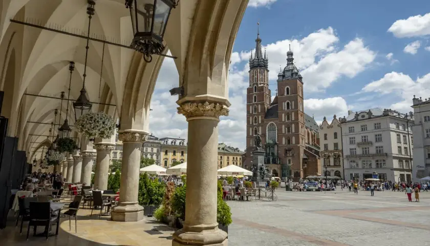 Podcienia Sukiennic w Krakowie, z widokiem na Rynek Główny i Kościół Mariacki. Stare miasto kraków tętni życiem.