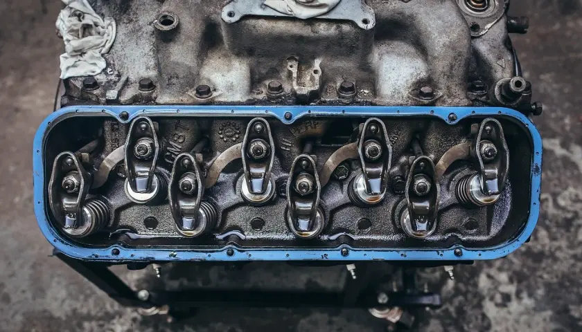 Detalle de balancines y resortes de un motor, con aceite visible, parte del sistema de lubricación.