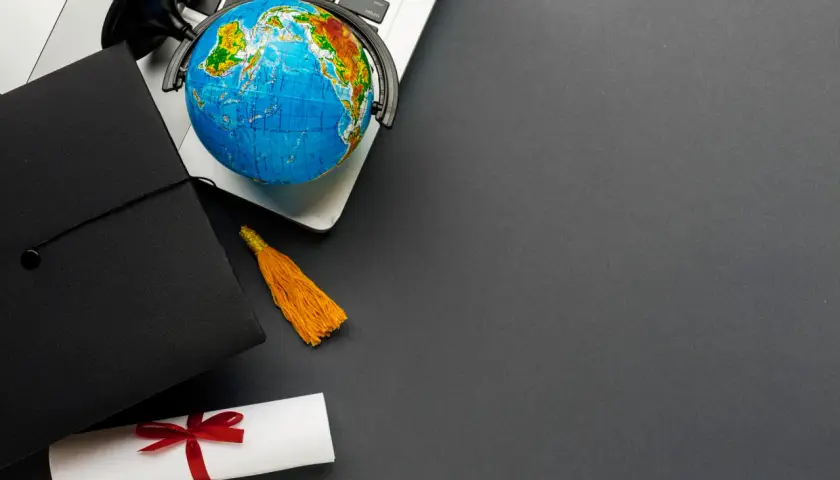 Dyplom, czapka absolwenta i globus na laptopie symbolizują globalne wykształcenie i nostryfikację.