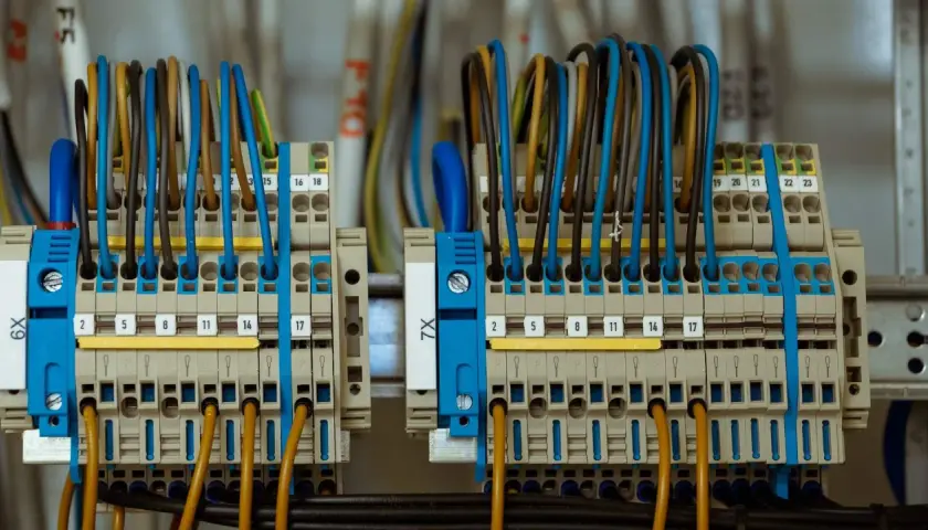 Starannie wykonane przyłącze elektryczne z wieloma przewodami w różnych kolorach, podłączonymi do zacisków.