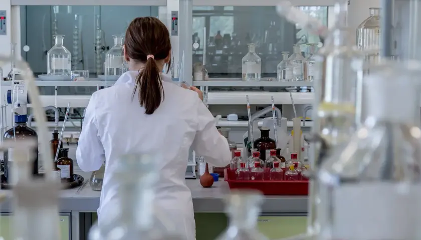 Naukowczyni w białym fartuchu pracuje w laboratorium, otoczona szkłem laboratoryjnym. Analizuje próbki, być może badając rdw-cv.