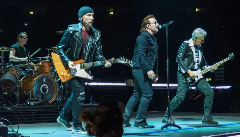 Bono śpiewa, The Edge gra na gitarze, a Adam Clayton na basie. Ich muzyka to pieśń protestu, która porusza tłumy.