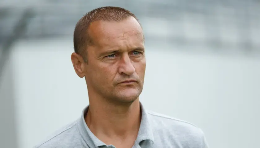 Dariusz Dźwigała w szarym polo, zamyślony, patrzy w bok.