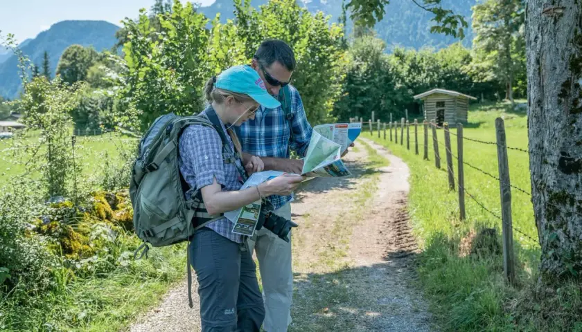Zwei Wanderer mit Rucksäcken studieren eine Karte, um ihre Route zu planen. Die Packliste fürs Pilgern ist wichtig für die Tour.