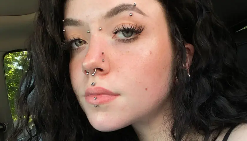 Dziewczyna z wieloma kolczykami, w tym kolczyk w brwi, septum i na ustach.