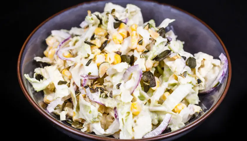 Frischer Chinakohl Salat mit Mais, roten Zwiebeln und Kürbiskernen in cremiger Soße.