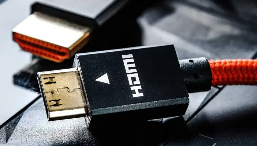 Złote wtyczki HDMI, jeden z nich z czerwonym, plecionym kablem, gotowe do podłączenia.