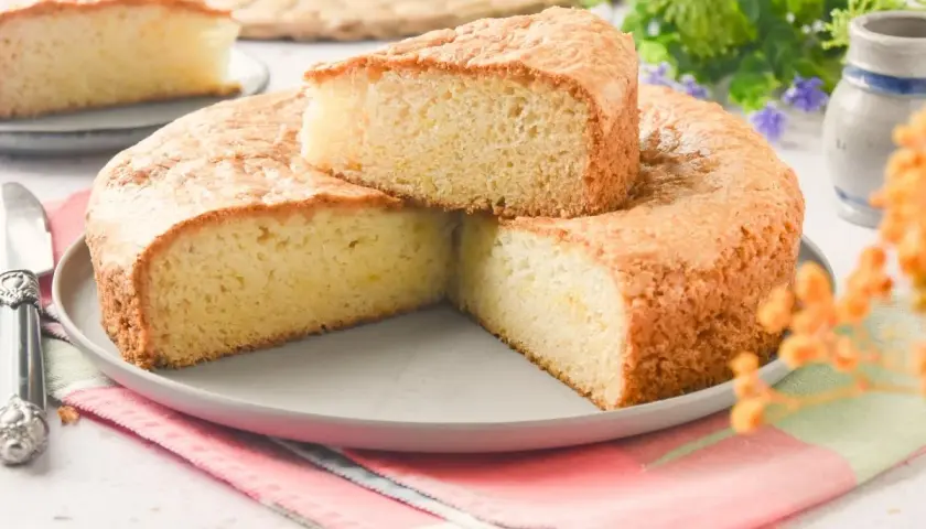 Bizcocho sin huevo esponjoso y dorado, servido en plato gris con servilleta colorida. Perfecto para un postre ligero.