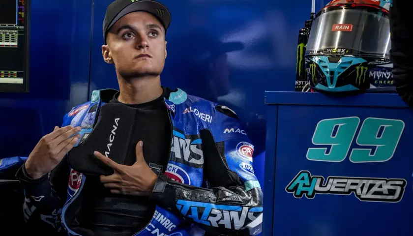 Adrian Huertas, piloto de motociclismo, con su casco y mono azul. El número 99 destaca en el fondo.
