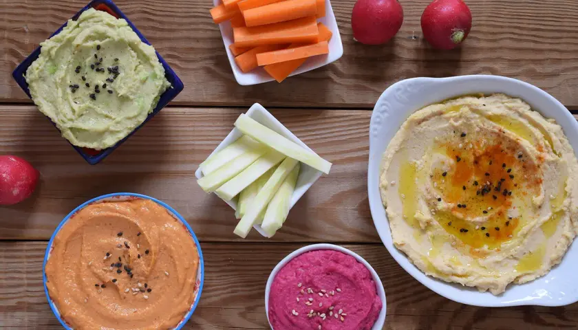 Variedad de hummus, zanahorias, apio y rábanos. Ideas para recetas de hummus saludables y deliciosas.