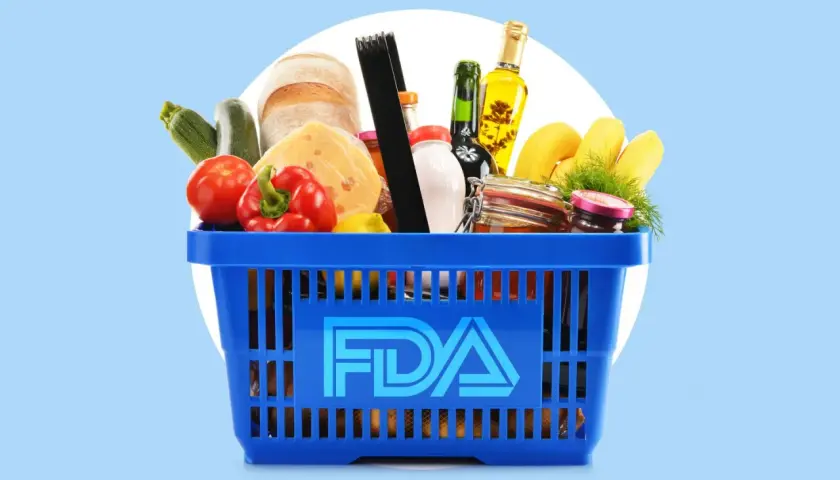 A blue shopping basket filled with groceries, including bread, cheese, and produce, with the FDA logo prominently displayed. This image represents food safety regulations overseen by the FDA and USDA.