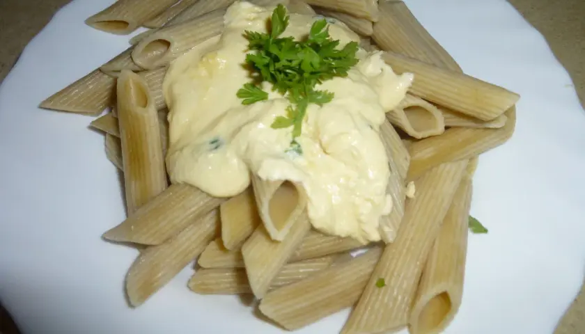 Penne z kremowym sosem pomidorowym z ricottą, udekorowane natką pietruszki. Pyszne danie gotowe w kilka minut.