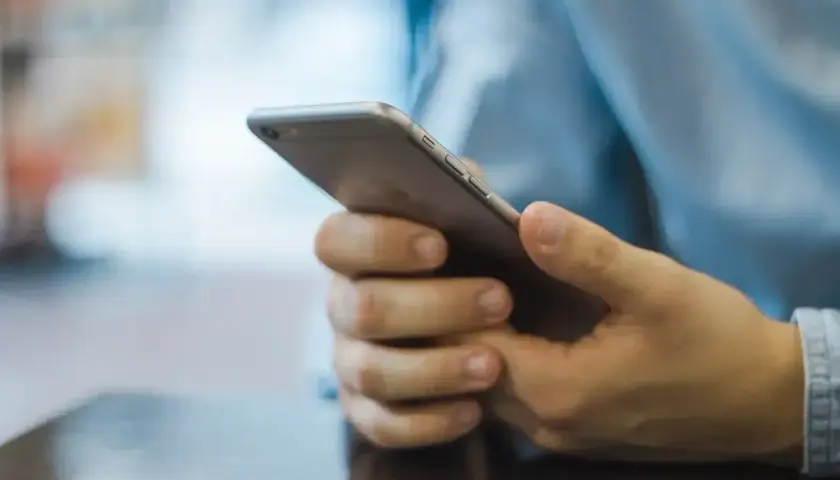 Mężczyzna trzyma telefon, zastanawiając się, jak zacząć rozmowę na Badoo.
