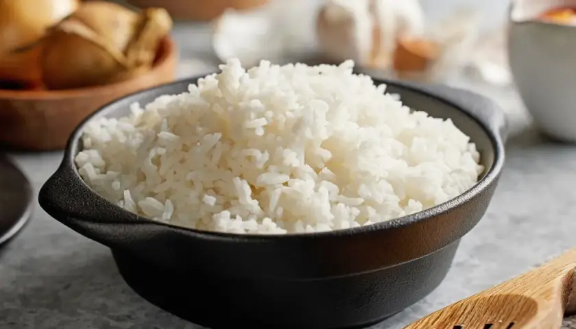 Un bol de riz blanc moelleux, prêt à être dégusté. Saviez-vous pourquoi rincer le riz avant cuisson ? Cela enlève l'excès d'amidon pour un résultat plus léger.
