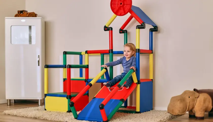 Kleines Kind rutscht auf bunter Spielburg. Tolle quadro aufbau ideen für das Kinderzimmer.