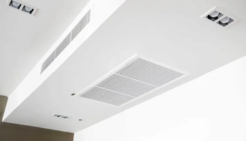 Sufit z kratkami wentylacyjnymi, w tym duży prostokątny element i długi węższy, świadczą o sprawnie działającej klimatyzacji kanałowej.
