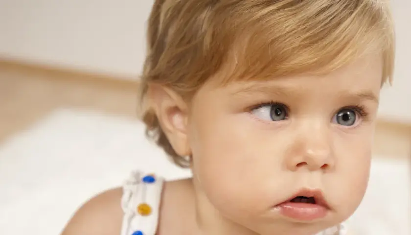 Primo piano di un neonato con occhi chiari. Uno sguardo attento, forse un caso di falso strabismo nei neonati, che spesso si risolve da solo.