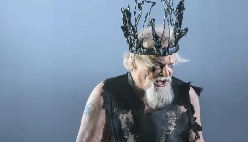 En skådespelare som Kung Lear på Dramaten, med en taggig, svart krona och trasiga kläder.