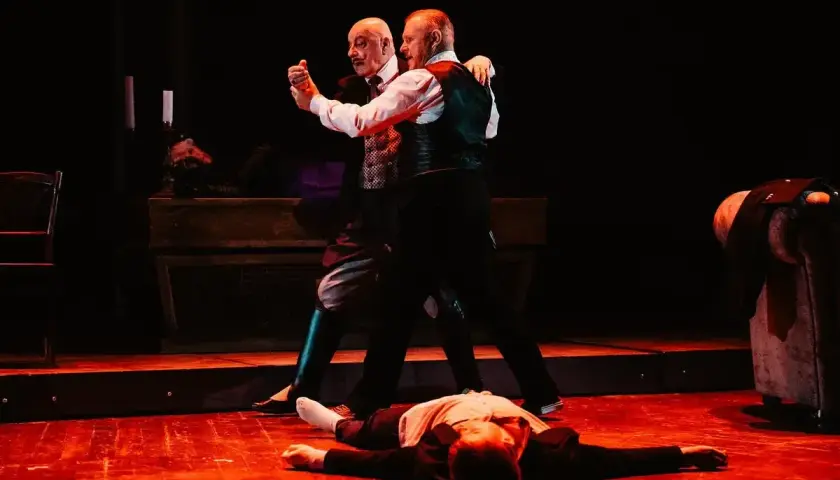 Dwóch mężczyzn tańczy tango na scenie, podczas gdy trzeci leży na podłodze. Edek Tango w akcji.