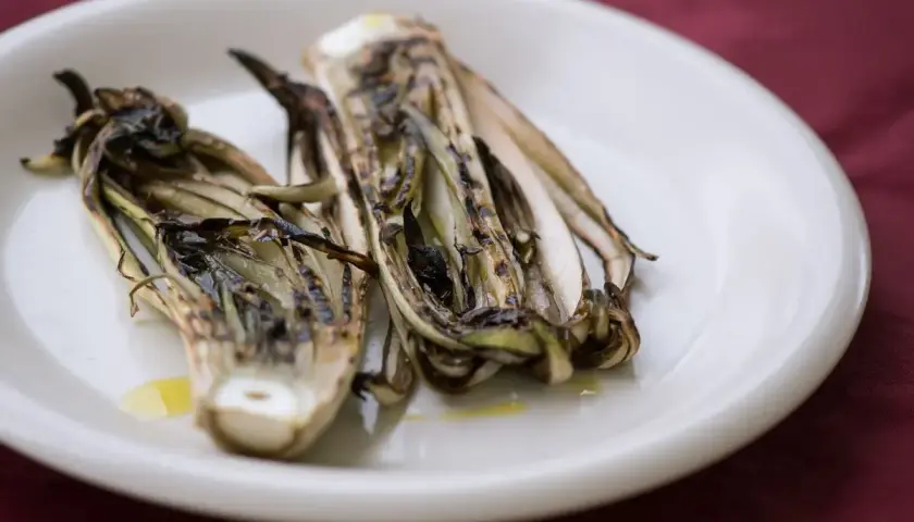 Radicchio grigliato in friggitrice ad aria, servito su un piatto bianco con un filo d'olio.