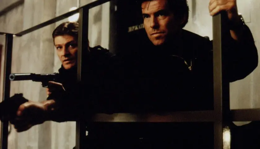 Pierce Brosnan och en kollega i actionfyllda filmer. De är redo för strid med vapen i hand.