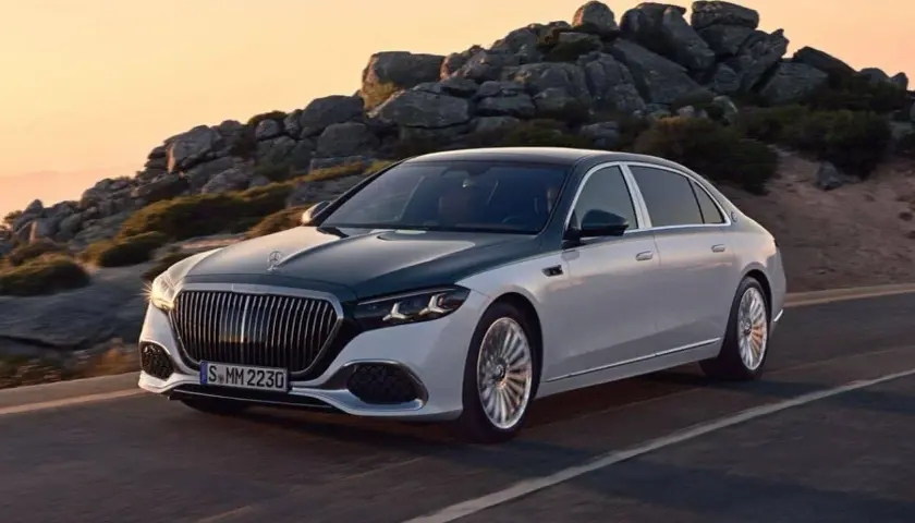 Elegancki, dwukolorowy Maybach, uznawany za najbardziej luksusowy samochód na świecie, sunie po górskiej drodze o zachodzie słońca.