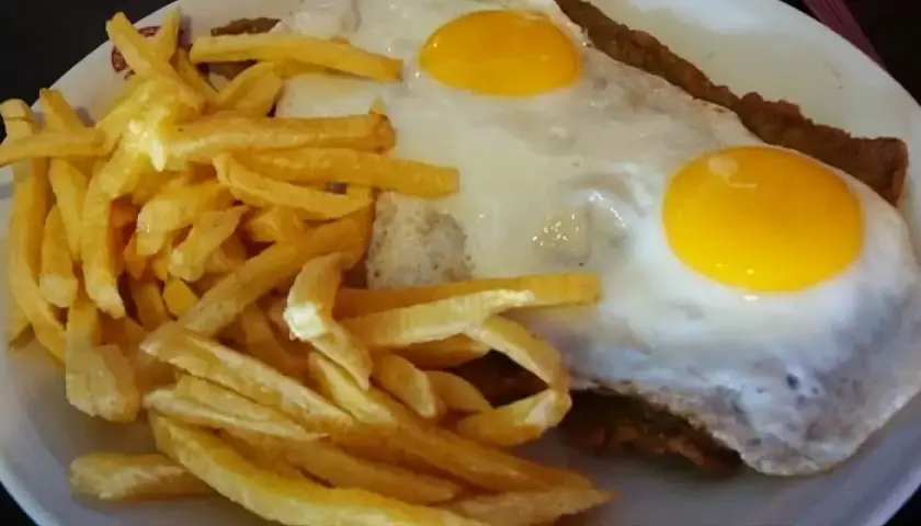 Un delicioso plato de milanesa a caballo, con dos huevos fritos y papas fritas crujientes.