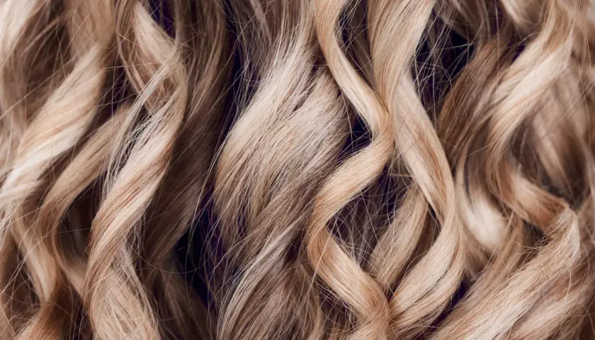 Falujące, jasne blond włosy z subtelnymi refleksami. To efekt flamboyage, techniki rozjaśniania nadającej naturalny wygląd.