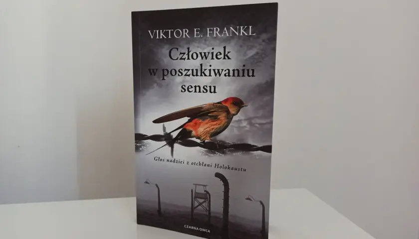 Okładka książki "Człowiek w poszukiwaniu sensu" Viktora Frankla. Ptak siedzi na drutach kolczastych, symbolizując nadzieję w mrocznych czasach.